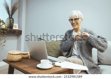 I love you. A grateful loving mature woman poses for the interlocutor and holds her heart with her fingers close to her chest. The happy woman looks at the camera as a gesture of gratitude