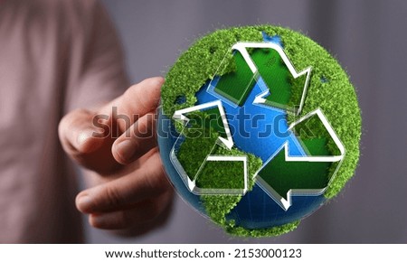 A closeup of a person touching a 3D render of the earth with the symbol "recycle" on it