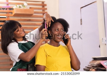 african lady making a phone call while is being done Royalty-Free Stock Photo #2153002099