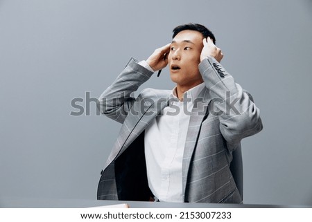 Asian man in a gray suit in the office with a notepad on the table the idea of writing Lifestyle