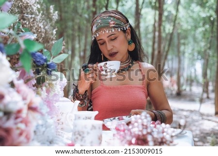 Beautiful woman in vintage dress resting in the garden. He was enjoying his morning coffee happily on the table. decorated with flowers.
