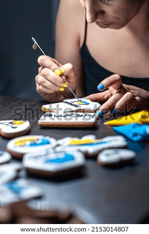 A woman makes gingerbread with the symbols of Ukraine, covers with icing, handmade cookies in support of Ukraine.