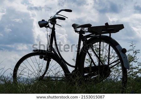 Silhouette of a classic bicycle on a cloudy sky background