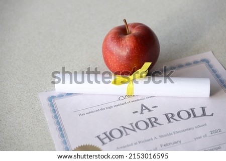 A honor roll lies on table with small scroll and red apple. Education documents close up Royalty-Free Stock Photo #2153016595