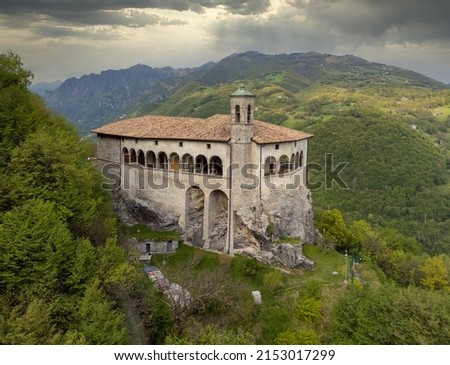 Aerial panoramic view from the drone of the Sanctuary of St. Patrick (San Patrizio) built on the sheer cliff, Colzate, Bergamo, Italy