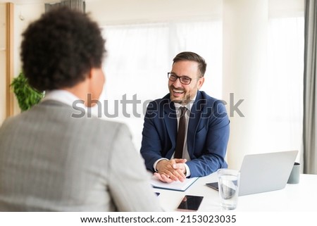 Handsome HR manager interviewing young african american women job applicant in the office. Confident businessman consulting client at meeting, business conversation Royalty-Free Stock Photo #2153023035