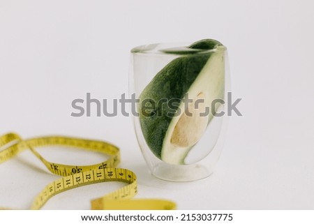Glass of water, avocado is in the glass of water. diet. healthy food. colorful pictures. measure ripe for body shapes. concept of beauty and healthy lifestyle