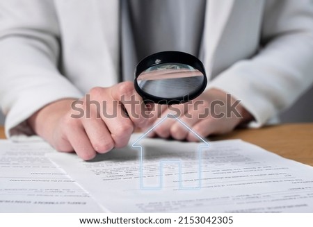 Woman hands holding magnifier and studying real estate purchase, lease or home loan agreement. Thorough analysis of contract terms and conditions. Apartment or house buying or sale. High quality photo