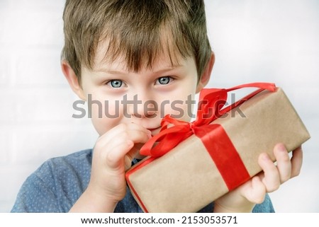 portrait of a blue-eyed boy 4-5 years old, with a gift in his hands. cute baby looks into the frame, horizontal photo.