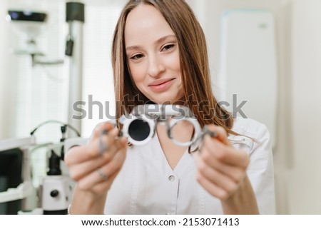 Attractive woman ophthalmologist with a trial frame for the selection of complex glasses, astigmatic, prismatic and for ophthalmological examination. advertising of the optics salon. selective focus Royalty-Free Stock Photo #2153071413