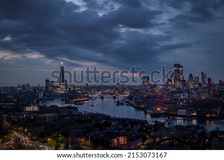 Panoramic view of the illuminated skyline of London with City, Tower Bridge and skyscrapers during a moody evening
