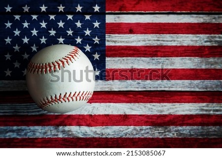 Leather baseball on rustic wooden background painted with US flag and copy space.