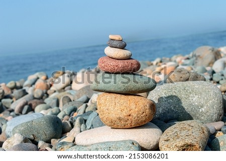 Close up of orange, red, blue and white rocks stacked one on top of another with soft selective focus. Colorful stones are naturally balanced on the background of the sea. 