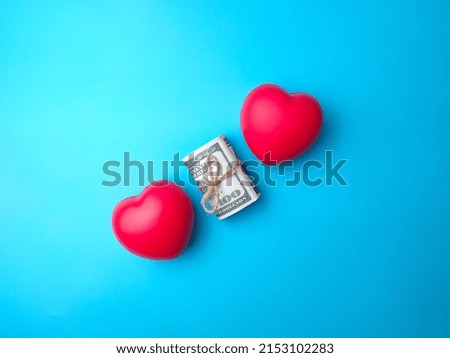 Top view banknotes and two red heart shape on blue background. Money and love concept.
