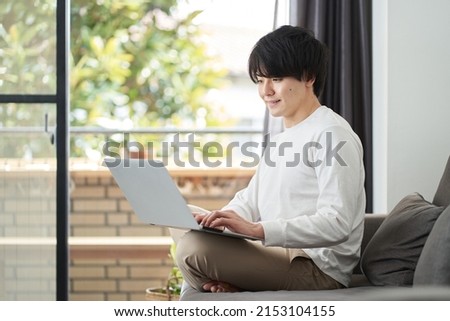 Asian man using a computer in his living room Royalty-Free Stock Photo #2153104155
