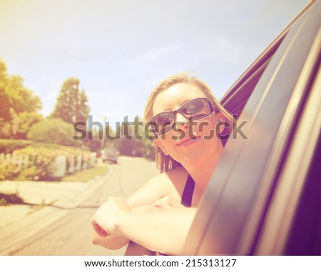  a pretty woman with her head out the window of a car driving down the street 
