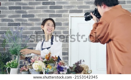 Asian female clerk photographed by a cameraman. Article coverage. Store promotion.