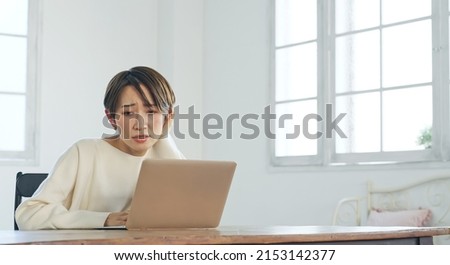 Asian middle-aged woman in trouble while looking at a laptop PC.