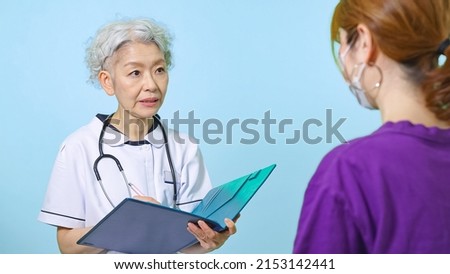 Asian senior woman in a lab coat treating a patient.