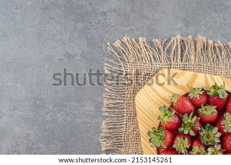 Heap of fresh strawberries in wooden plate on marble table, Strawberries in wooden bowl. Fresh strawberries. Juice strawberry, Fresh ripe organic strawberry, concrete background. Top view copy space.