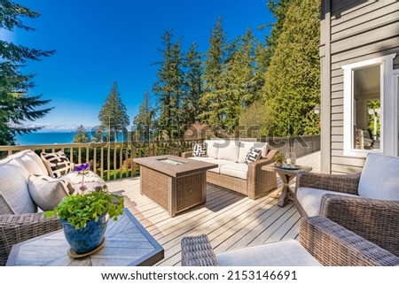 outdoor living deck furnished with resin wicker fire table and ocean view Royalty-Free Stock Photo #2153146691
