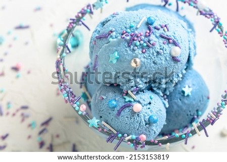 Balls of artisanal blue ice cream served with multicolored sugar sprinkles, close-up, selective focus. Concept of summer desserts.