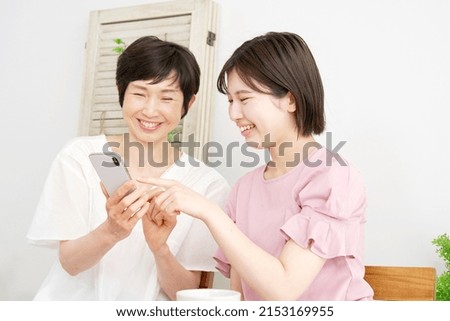 Asian daughter using the smartphone with her mother at home