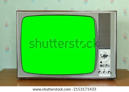 Old vintage green screen TV in a room with vintage wallpaper. Interior in the style of the 1960s. Royalty-Free Stock Photo #2153171433