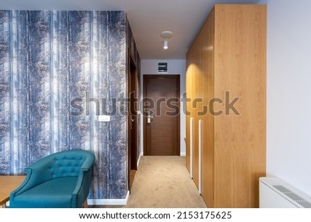 Interior of a carpeted hotel corridor doorway with brown wooden doors