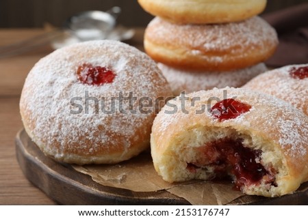Delicious donuts with jelly and powdered sugar on wooden board, closeup Royalty-Free Stock Photo #2153176747