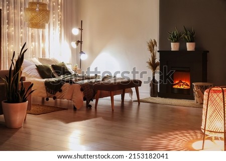 Interior of stylish bedroom with fireplace in evening