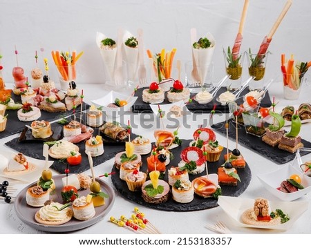 Mini snacks on a white background. Cold appetizer. On a black serving board. Snacks for public catering . Catering. Buffet table. Catering. Royalty-Free Stock Photo #2153183357