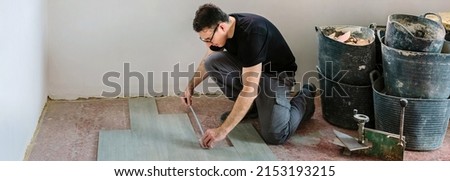 Bricklayer laying and measuring tiles to install a floor