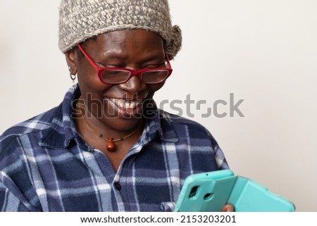 Portrait cheerful excited old black african woman receiving good news with her smartphone. Happy senior lady using mobile phone