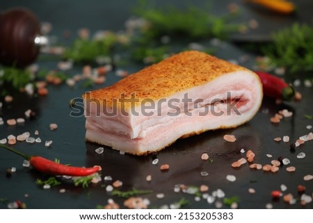 macro shot of a large piece of lard isolated on a black background with space for text with different seasonings and herbs