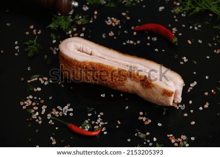 macro shot of a large piece of lard isolated on a black background with space for text with different seasonings and herbs