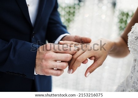 The groom wears a ring to the bride at the wedding ceremony Royalty-Free Stock Photo #2153216075