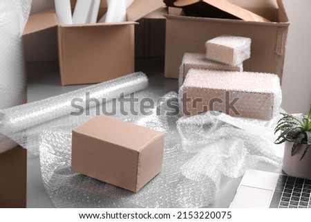 Table with laptop, boxes and bubble wrap in warehouse Royalty-Free Stock Photo #2153220075
