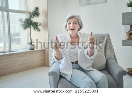Happy older citizen looking at webcamera, speaking at job interview. Videocalling allows for an online interaction. Senior vlogger begins livestreaming and video recording for social media. Royalty-Free Stock Photo #2153223001