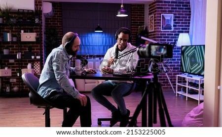 Online vlogger filming podcast episode with man in studio, using camera and soung production equipment to record. Content creator broadcasting live conversation on social media. Royalty-Free Stock Photo #2153225005