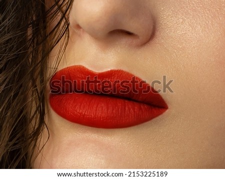 The macro photo of the closed female mouth. Chubby lips with red lipstick show a fashionable make-up and increase in lips. Cosmetology, Spa, cosmetics
