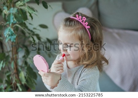 Cute little girl is playing in a beauty salon. Beautiful girl of 3 years old makes makeup with children's cosmetics at home. Spring.