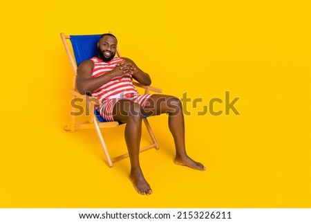 Photo of guy sit deck chair enjoy exotic recreation wear swim striped set shorts isolated bright color background