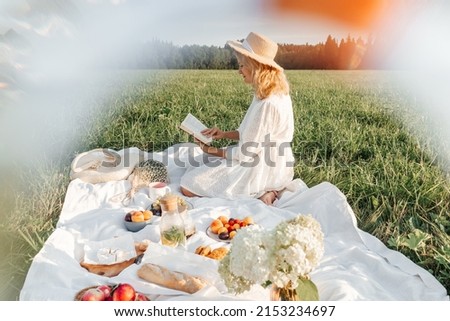 Woman read book on picnic in field.