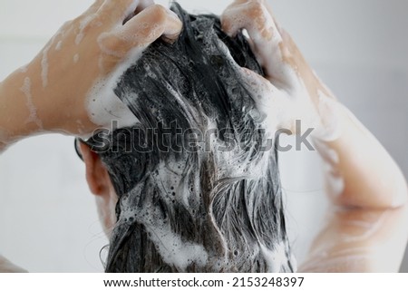 Woman is washing her hair with shampoo Royalty-Free Stock Photo #2153248397