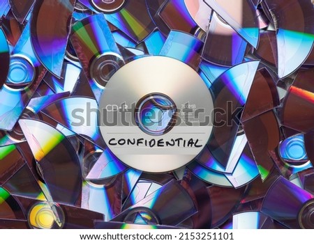 CD with confidential written on it, with shredded CD's and DVD's in the background. Royalty-Free Stock Photo #2153251101