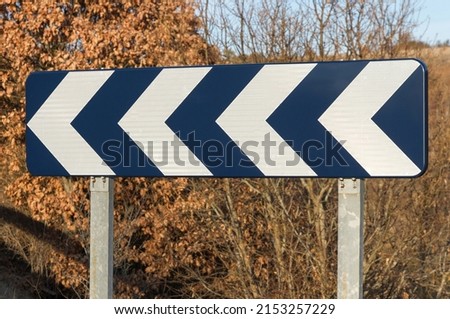 Traffic sign with arrows indicating Dangerous curve to the left in Road  Royalty-Free Stock Photo #2153257229
