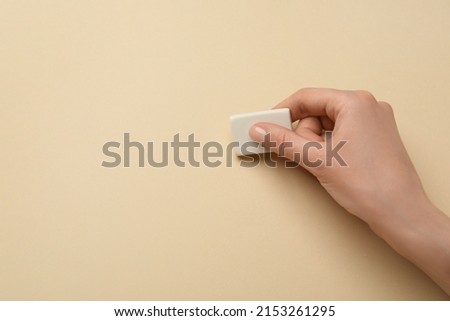 Woman erasing something on beige background, closeup. Space for text Royalty-Free Stock Photo #2153261295