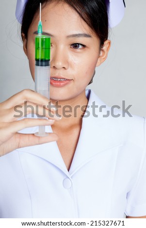 Young Asian nurse look at syringe on gray background