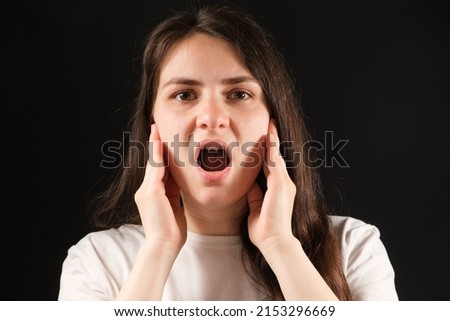 A woman with an open mouth holds her cheeks with her hands, exercises for dysfunction of the temporomandibular joint Royalty-Free Stock Photo #2153296669